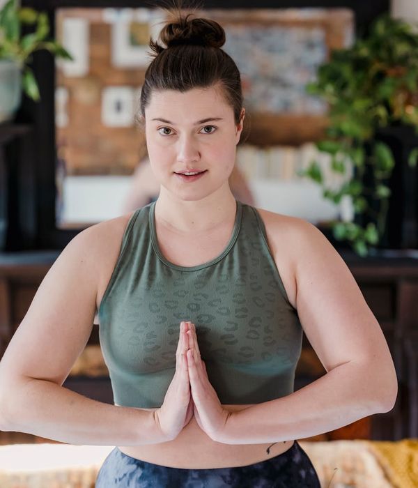 Woman in a calm yoga pose in a dark room with lime green light.